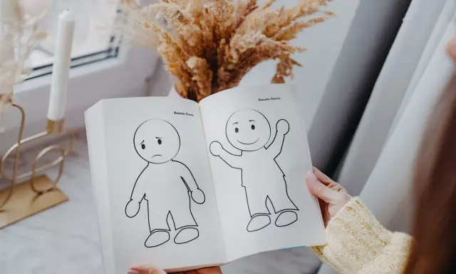 Otwarta książka pokazuje rysunki smutnego i radosnego dziecka, symbolizujące nasze wewnętrzne dziecko.