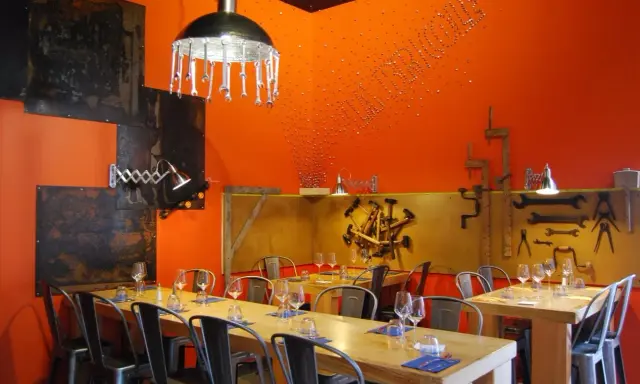 Ambiance industrielle dans un des restaurants de Chambray-lès-Tours. Tables dressées, murs orange vif, luminaires originaux.