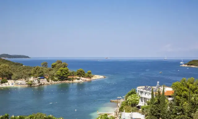 Piękna zatoka w Ksamil, Albania, z turkusową wodą, zielonymi wyspami i białym hotelem. Idealne miejsce na wakacje.