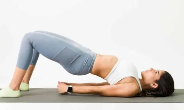 Mujer haciendo puente en colchoneta, ejercicio para fortalecer glúteos y mejorar cómo dormir para que no te duela la espalda.