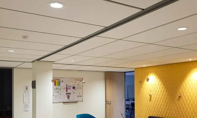 Plafond fibralith blanc, discret, avec des spots lumineux intégrés. Une ambiance moderne et épurée.