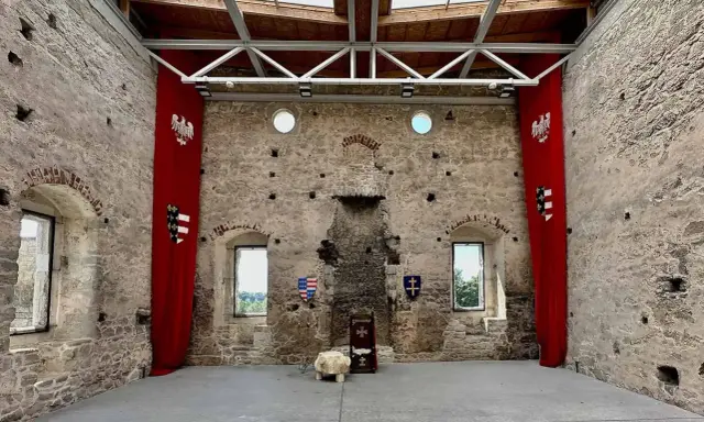 Wnętrze zamku w Szydłowie. Czerwone banery z orłami i herbami, tron. Sprawdź cennik zwiedzania!