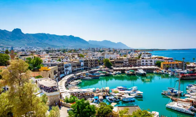 Kyrenia, Cypr, gdzie najcieplej, z malowniczym portem pełnym łodzi i górami w tle.