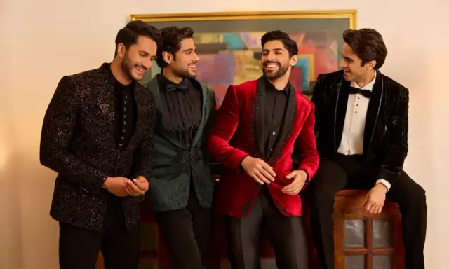 Four men in stylish winter wedding attire, showcasing embellished jackets in black, green, red, and velvet.
