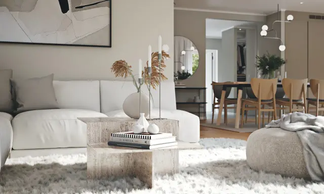 En modern lounge med en vit soffa, ett soffbord i sten och en fluffig matta. I bakgrunden syns en matsal med trästolar, vilket visar olika inredningsstilar.