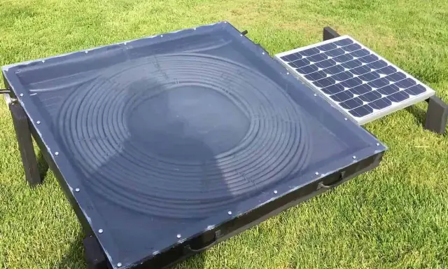 Un système de chauffage air solaire avec un panneau de tubes noirs en spirale sous une couverture transparente, à côté d'un petit panneau solaire.
