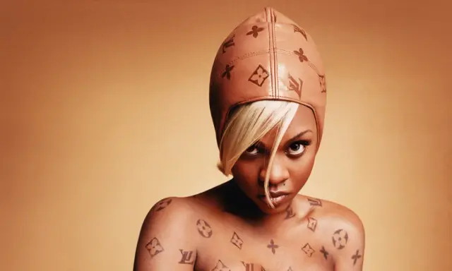 Lil' Kim w skórzanej czapce i z tatuażami Louis Vuitton na ciele.