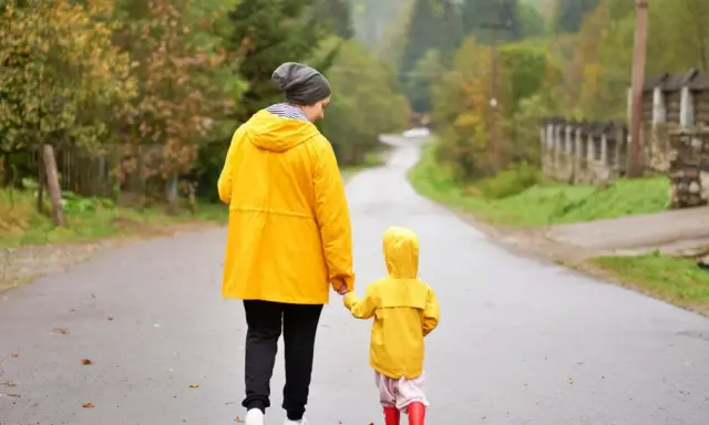 Mama i dziecko w żółtych płaszczach idą drogą. Nawet w deszczową pogodę Jastrzębia Góra oferuje atrakcje na niepogodę, jak wspólne spacery.