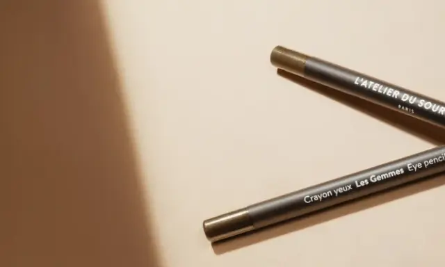 Deux crayons pour les yeux L'Atelier du Sourcil, un avant et un après, sur fond beige.