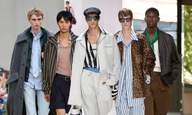 Five models showcase bold gay men fashion on a runway, featuring a mix of stripes, leopard print, and stylish outerwear.