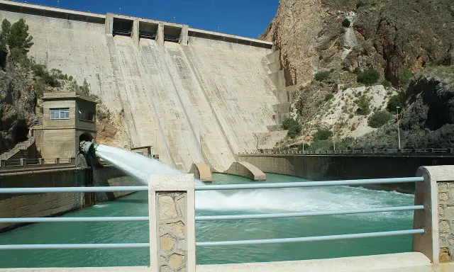 El embalse del Cenajo libera agua a través de un gran conducto, creando una cascada espumosa en el río.