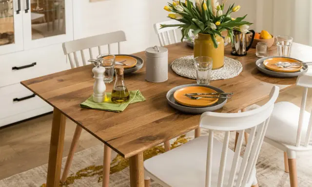 Elegancka, codzienna dekoracja stołu w salonie: drewniany blat, żółte tulipany, oliwa i przyprawy.