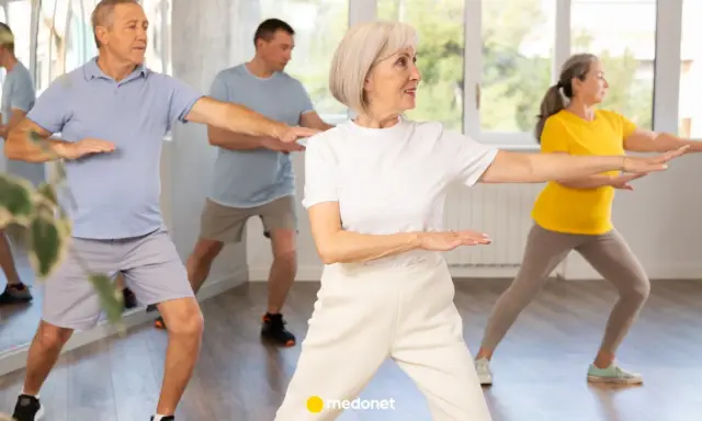 Seniorzy ćwiczą tai chi na krześle, poprawiając równowagę i spokój.