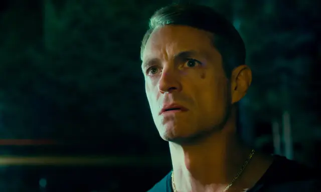 Joel Kinnaman i en mörk, intensiv scen från sin nya serie. Hans blick är fäst på något utanför bild, full av oro och beslutsamhet.