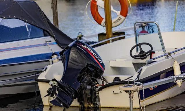 Moteur Mercury hors-bord sur un bateau blanc. Le moteur 2 temps ne démarre pas, il est temps de le réparer.