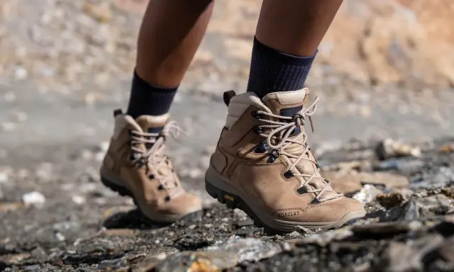 Botas de montaña Forclaz de color marrón, con cordones, sobre terreno rocoso.