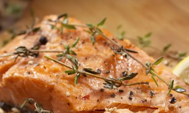 Delicioso salmón al horno con hierbas frescas y pimienta negra, listo para servir.