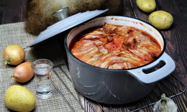 Herzhaftes russisches Essen: Ein Eintopf mit Speck überbacken, dazu Kartoffeln, Zwiebeln und Knoblauch.