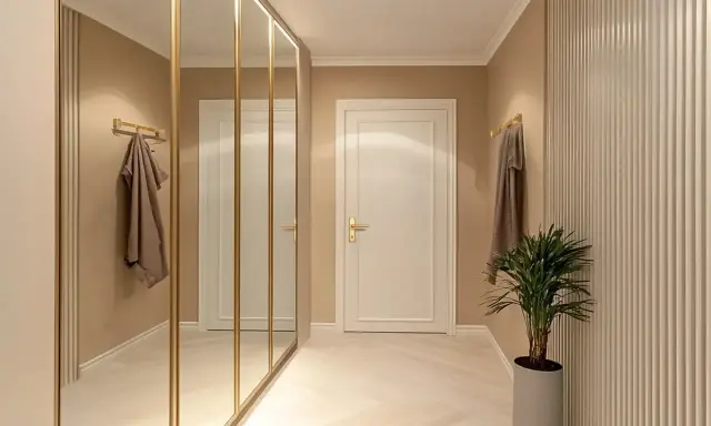 Elegancki przedpokój inspiracje ściany: lustrzana szafa, sztukateria i subtelne oświetlenie tworzą przytulną przestrzeń.