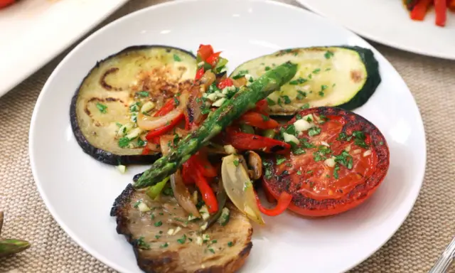 Deliciosa parrillada de verduras con berenjena, calabacín, tomate, pimientos y espárragos, todo aderezado con ajo y perejil.