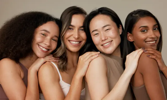 Quatre femmes souriantes aux teints variés, partageant un moment de complicité. Leur peau rayonne, signe qu'elles savent comment hydrater sa peau en profondeur.