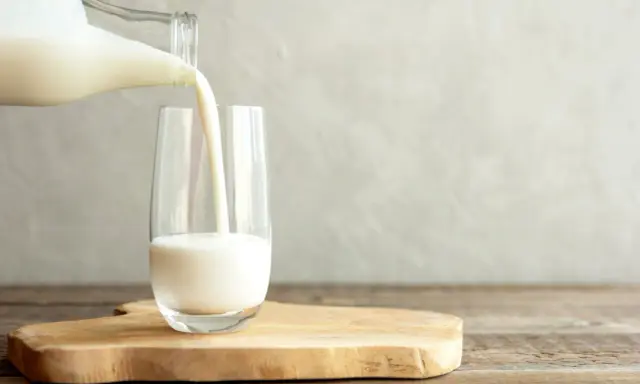 Kefir jest lekkostrawny, co widać na zdjęciu, gdy biały napój jest przelewany z butelki do szklanki.