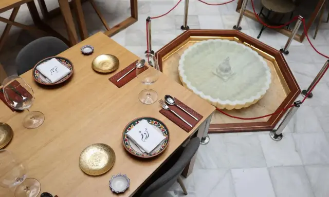 Mesa elegante en el restaurante El Puente El Tejar, con vajilla dorada y una fuente ornamental en el centro.