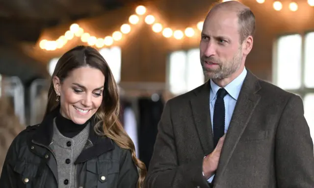 Prins William av Wales och Kate Middleton ler under en ljusslinga.