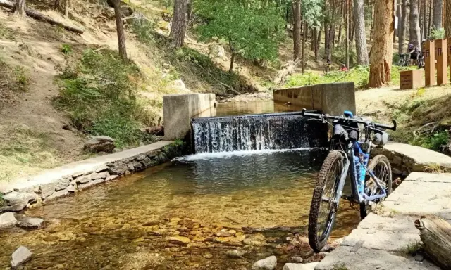 Bicicleta de montaña junto a una cascada en un arroyo, ideal para rutas por Segovia.
