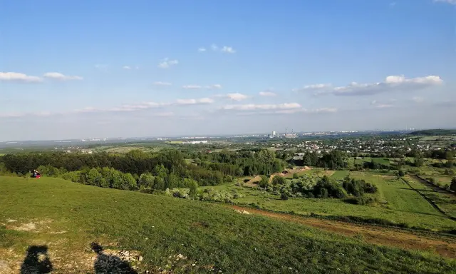 Widok z góry Siewierskiej na zielone pola i lasy, w oddali widać zabudowania i kominy.