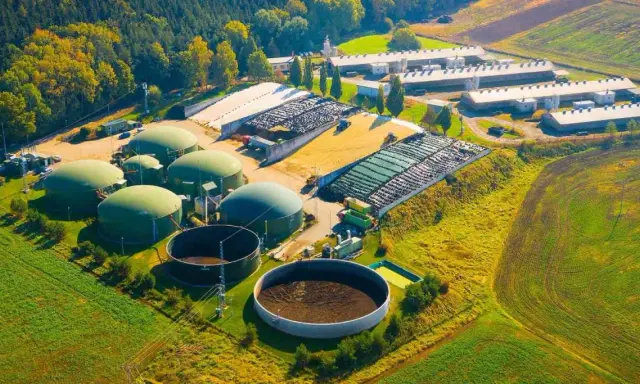 Planta de biogás con biodigestores y granjas. Las desventajas de la biomasa incluyen el uso de grandes extensiones de tierra y la necesidad de infraestructura.