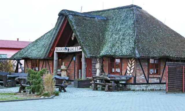 Skansen chleba z charakterystycznym, strzechą krytym dachem. Drewniane ławy i stoły zapraszają do odpoczynku.