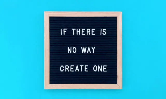 Czarna tablica z białym napisem "IF THERE IS NO WAY CREATE ONE" na niebieskim tle.
