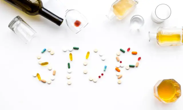 Nalewki, kieliszki i tabletki tworzą napis STOP. Różne rodzaje alkoholizmu i leczenia.
