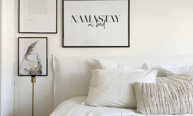 Un lit douillet avec une tête de lit DIY, des coussins texturés et des cadres muraux inspirants.