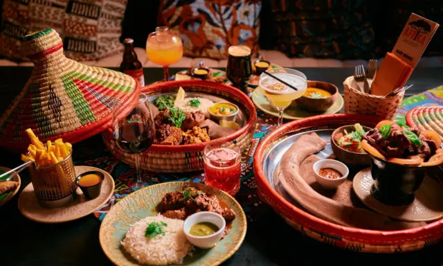 En härlig måltid på en afrikansk restaurang med flera rätter, drycker och en färgglad duk.
