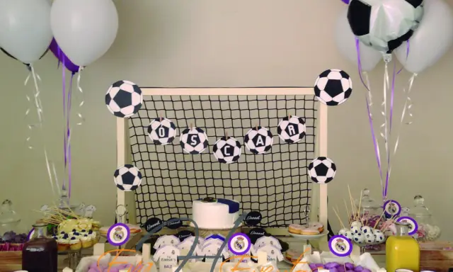 Mesa de chuches del Real Madrid: balones de fútbol, globos, tarta y dulces para una fiesta temática.