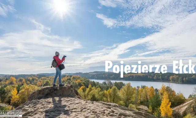 Idealne miejsce na weekend: dziewczyna z aparatem na wydmie podziwia jesienne krajobrazy nad Jeziorem Ełckim.