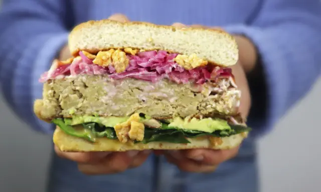 Hamburguesa de pollo con aguacate, col morada y crujientes trozos. ¡Una delicia!
