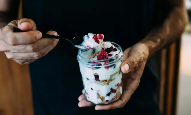 Ein Glas Magerquark mit Beeren, perfekt für den Muskelaufbau. Eine Löffelspitze voller Genuss.