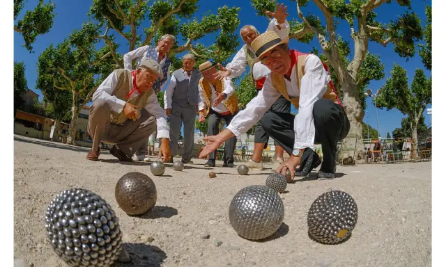 Des hommes jouent à la pétanque sous les platanes. La question "la pétanque est-il un sport ?" se pose devant leur concentration.