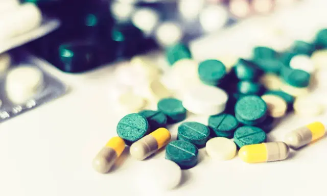 Rozrzucone tabletki i kapsułki, niektóre zielone, inne białe i żółte. Czy to lek na bóle mięśni, czy mogą wystąpić methocarbamol skutki uboczne?