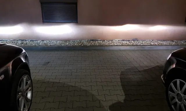 Jasne światła z przodu Audi A4 B6 oświetlają ścianę.
