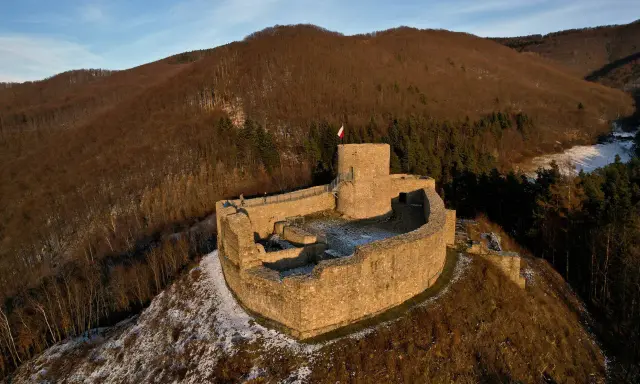 Ruiny zamku w Rytrze, z polską flagą na wieży. Warto sprawdzić zamek w Rytrze cennik przed wizytą.