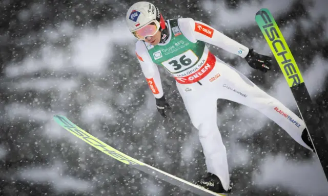 Skoczek narciarski w locie, przygotowuje się do lądowania. Widoczny numer 36. To może być zapowiedź skoki narciarskie 2026.