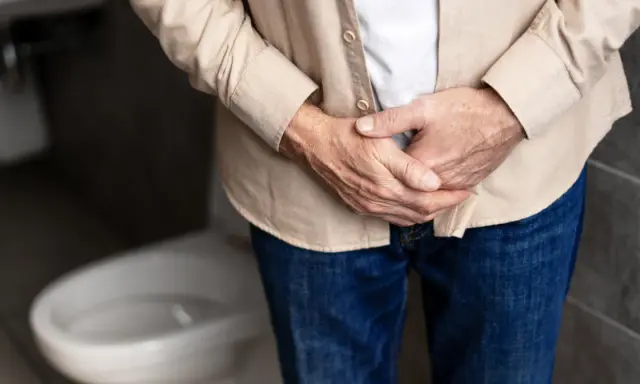 Mężczyzna trzyma się za podbrzusze, zastanawiając się, jakie badania na prostate są najlepsze.