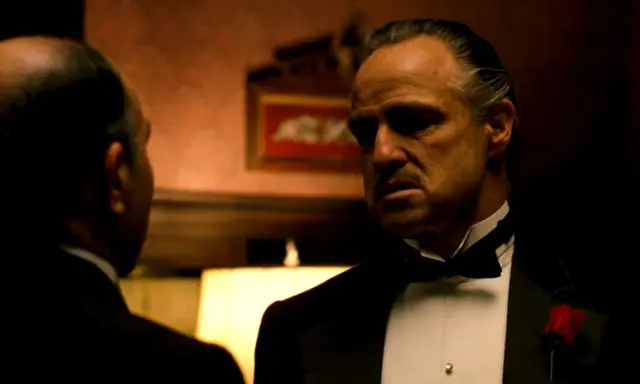 Marlon Brando nei panni di Don Corleone, un'icona de "Il Padrino", in una scena che riassume la sua recensione: potere e dramma.
