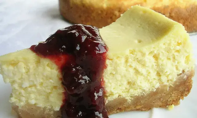 Pyszny sernik z serka wiejskiego polany wiśniową konfiturą, kusi swoim kremowym wnętrzem i chrupiącym spodem.