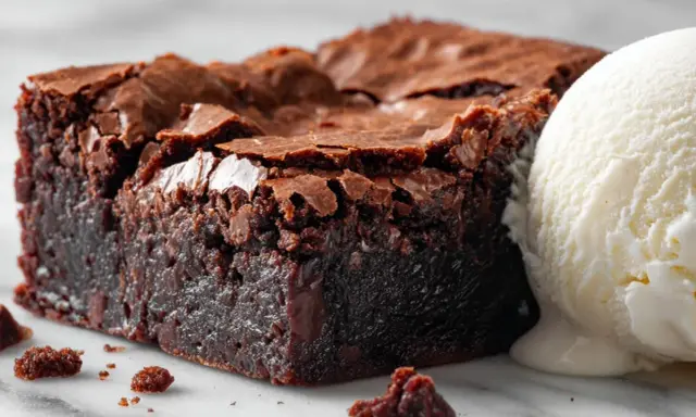 Un carré de tarte brownie, dense et chocolaté, avec une boule de glace à la vanille fondante. Un délice gourmand.
