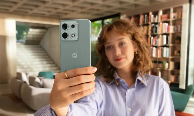 Kobieta robi selfie telefonem Motorola E6 Play w nowoczesnym wnętrzu.